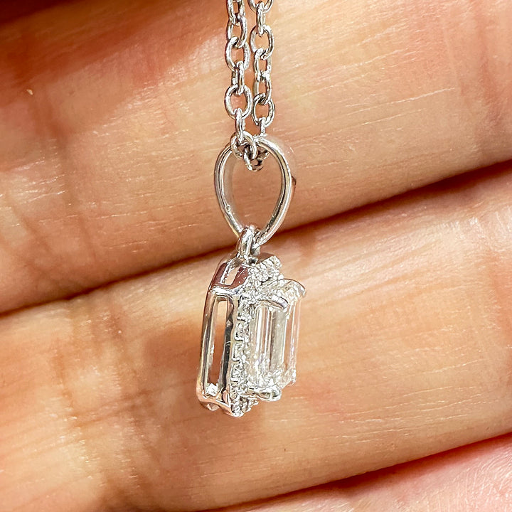 Close-up of a 10K white gold pendant featuring a 0.50ct emerald-cut lab diamond with a halo of smaller diamonds.