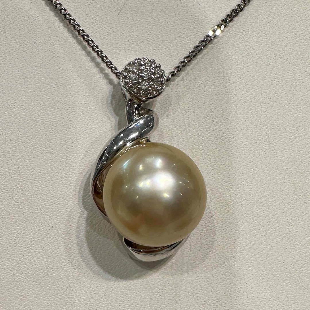 Close-up of a champagne-colored baroque South Sea pearl pendant in 14k white gold, featuring a unique spiral design with a diamond-studded top, total diamond weight 0.04 ct.