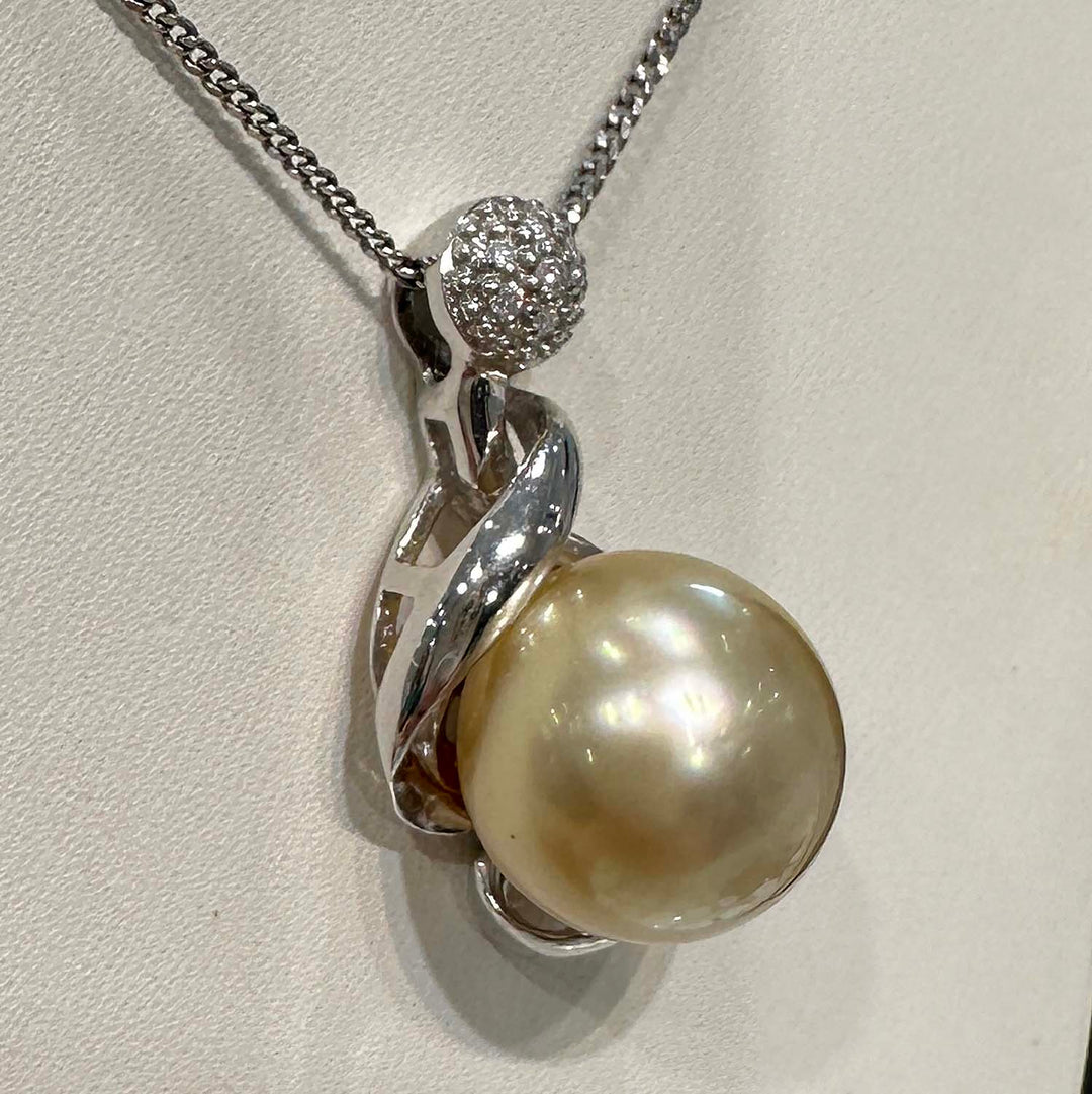 Close-up of a champagne-colored baroque South Sea pearl pendant in 14k white gold, featuring a unique spiral design with a diamond-studded top, total diamond weight 0.04 ct.