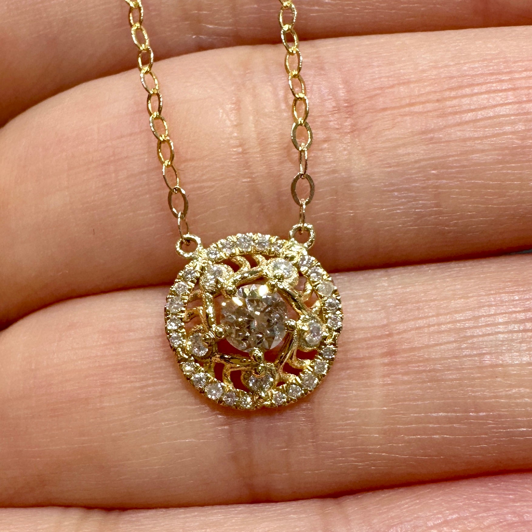 Close-up of a custom 14K gold pendant necklace with a 0.30 CT round diamond and halo setting on a delicate gold chain.