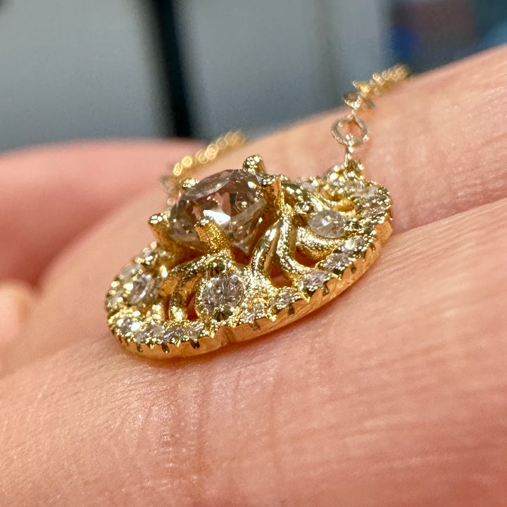 Close-up of a custom 14K gold pendant necklace with a 0.30 CT round diamond and halo setting on a delicate gold chain.