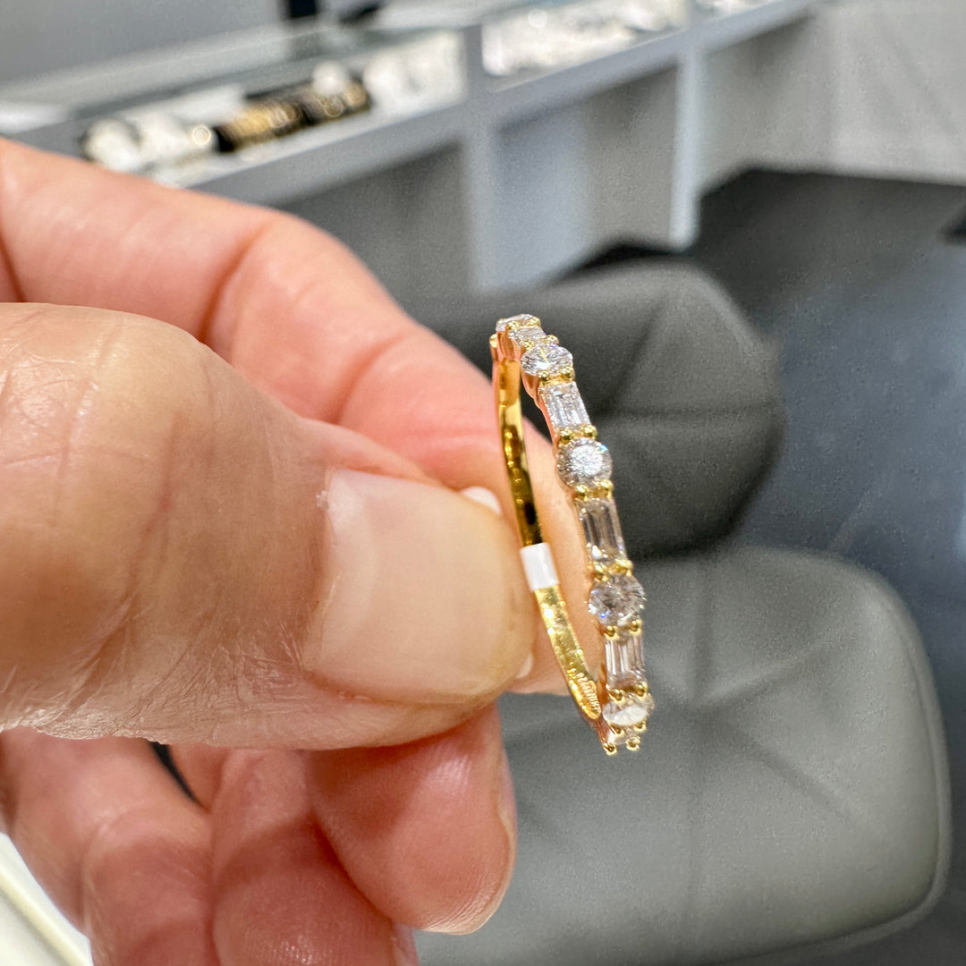 Close-up of a 14K yellow gold wedding band with round and baguette lab-grown diamonds in a unique, elegant design.