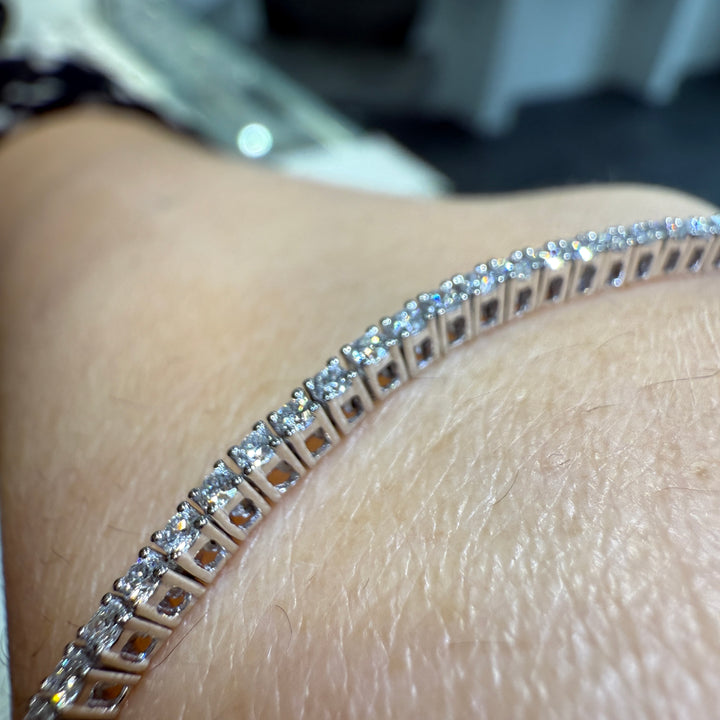 Close-up of a 14K white gold lab-grown diamond tennis bracelet with a four-prong, open-back basket-style setting, featuring 100 diamonds totaling 1.89 CT.
