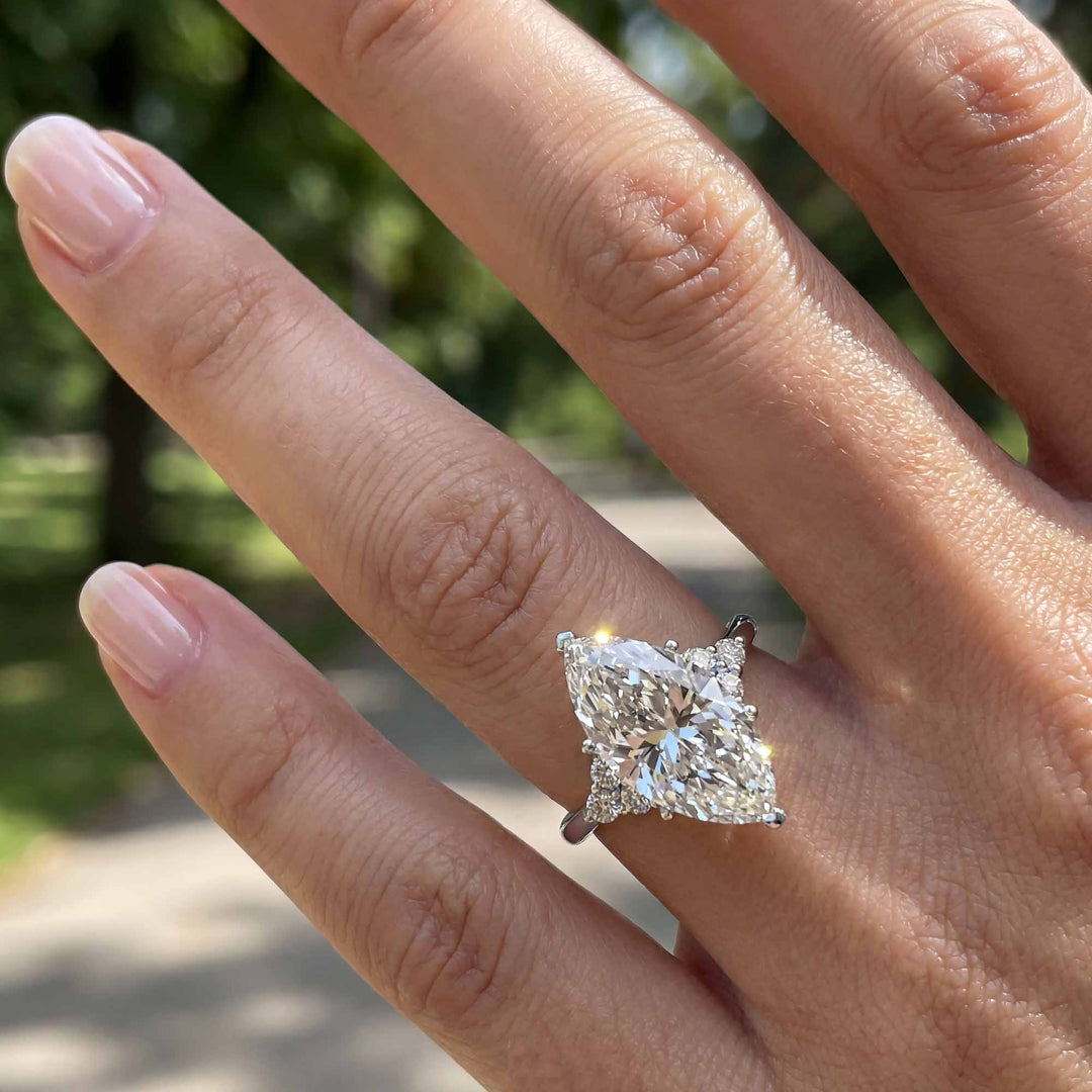 Marquise diamond engagement ring with clustered side diamonds on hand
