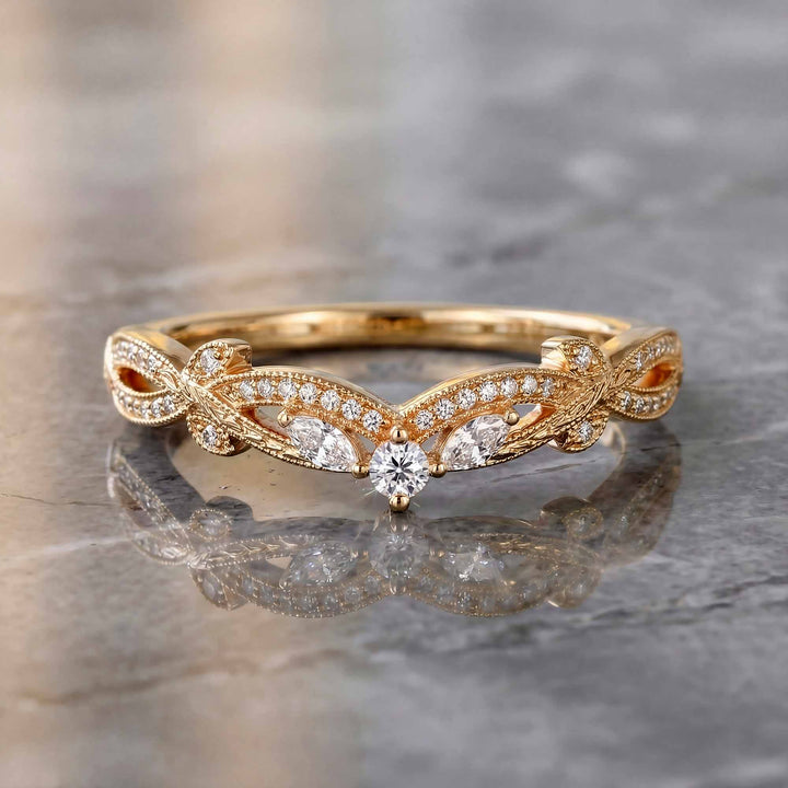 Curved wedding band with marquise and round lab-grown diamonds shown on reflective surface.