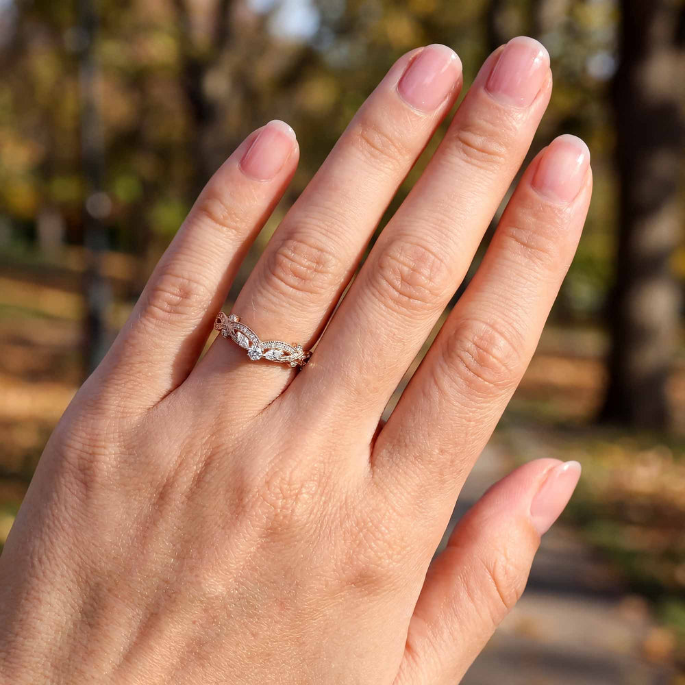 Curved wedding band with marquise and round lab-grown diamonds shown on reflective surface.