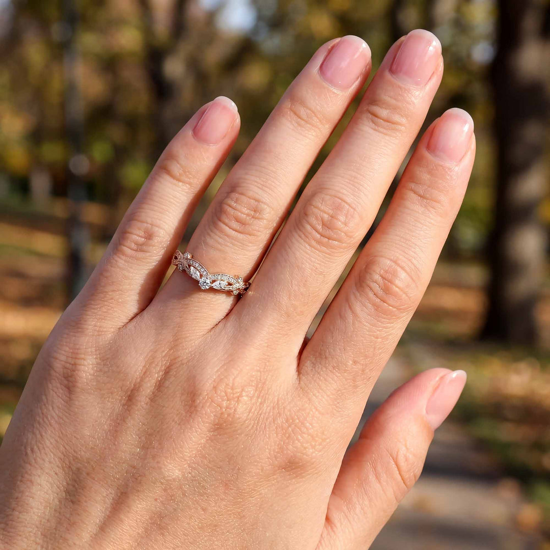 Curved wedding band with marquise and round lab-grown diamonds shown on reflective surface.