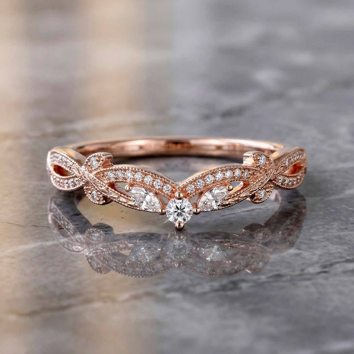 Curved wedding band with marquise and round lab-grown diamonds shown on reflective surface.