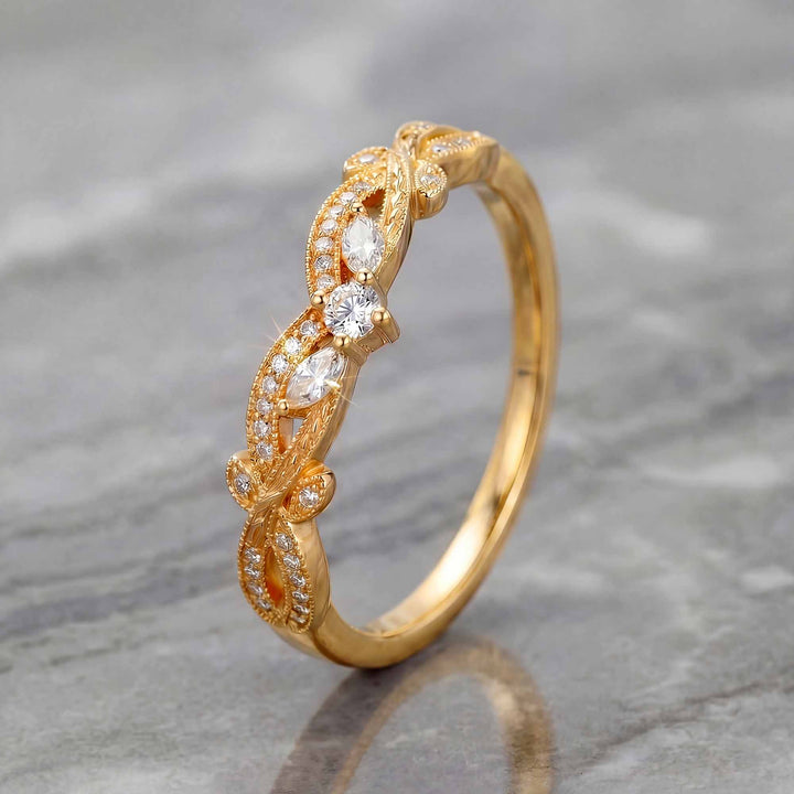 Curved wedding band with marquise and round lab-grown diamonds shown on reflective surface.