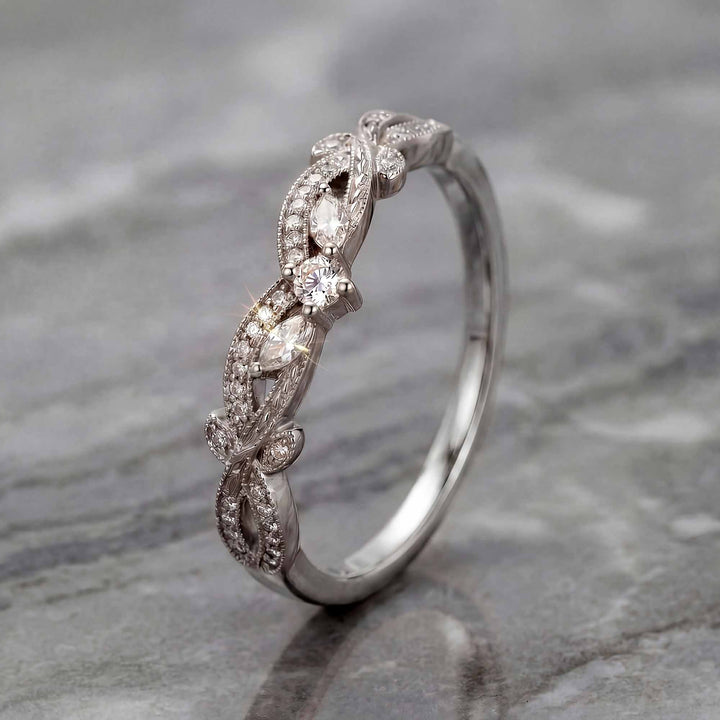 Curved wedding band with marquise and round lab-grown diamonds shown on reflective surface.