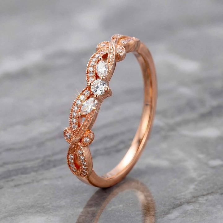 Curved wedding band with marquise and round lab-grown diamonds shown on reflective surface.