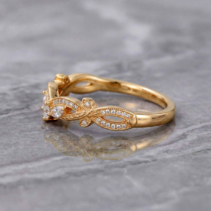 Curved wedding band with marquise and round lab-grown diamonds shown on reflective surface.