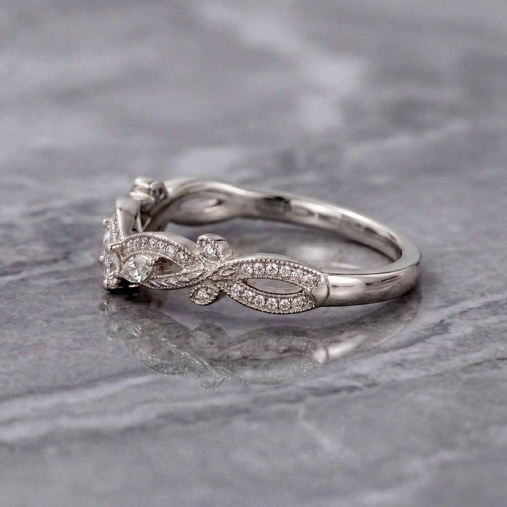 Curved wedding band with marquise and round lab-grown diamonds shown on reflective surface.