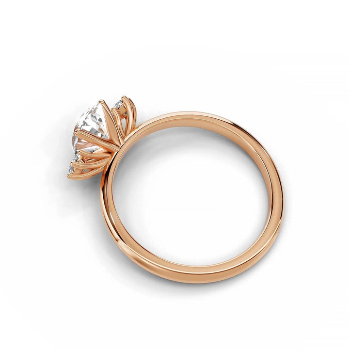 Oval diamond three-stone engagement ring in rose gold with round side stones.