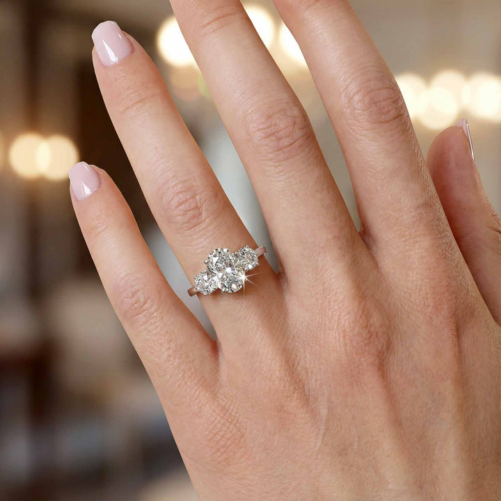 Oval diamond three stone engagement ring with round side stones and pavé band on display.
