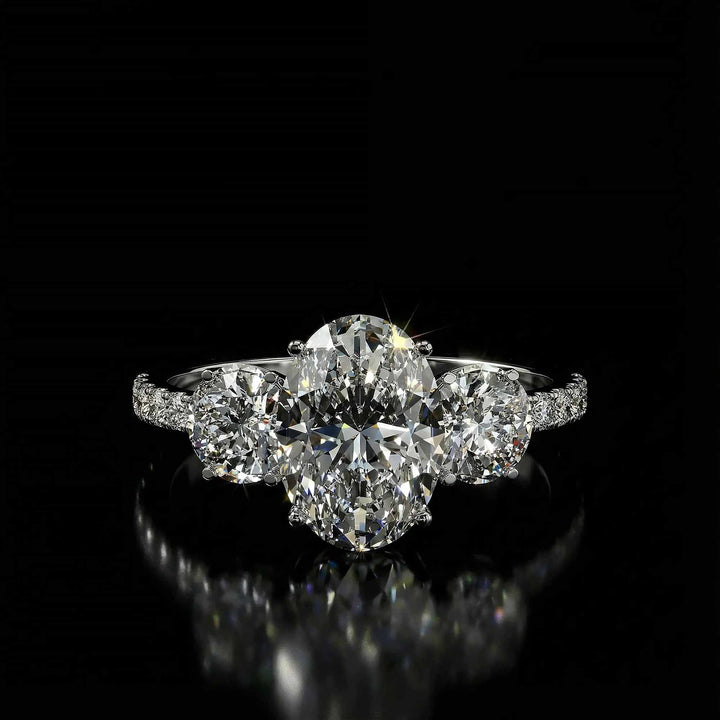 Oval diamond three stone engagement ring with round side stones and pavé band on display.
