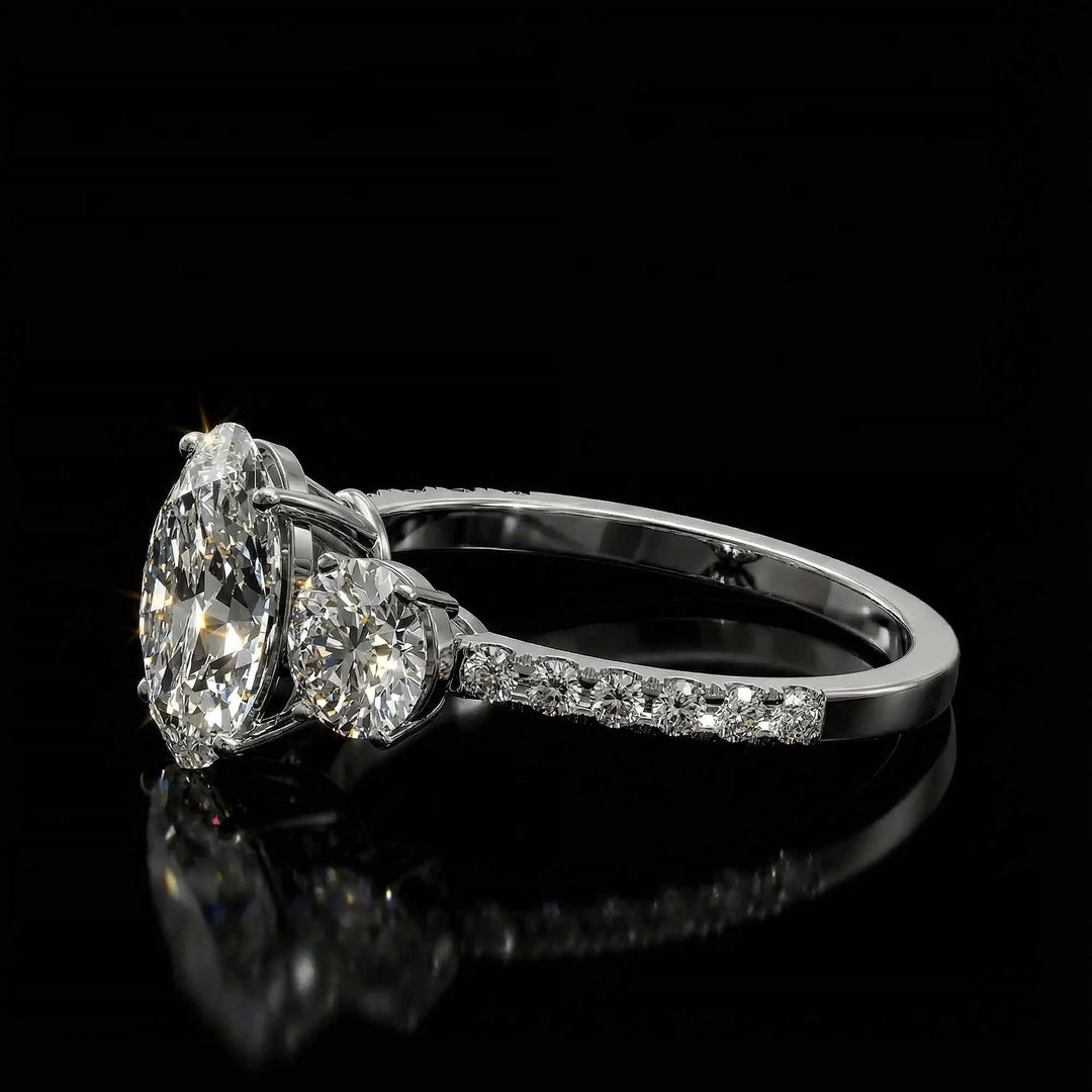 Oval diamond three stone engagement ring with round side stones and pavé band on display.
