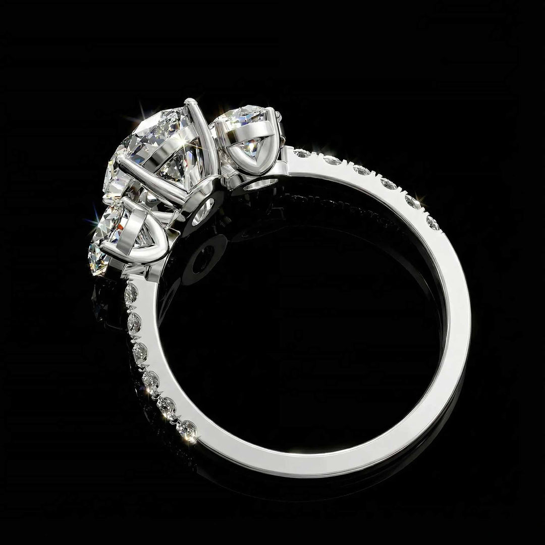 Oval diamond three stone engagement ring with round side stones and pavé band on display.