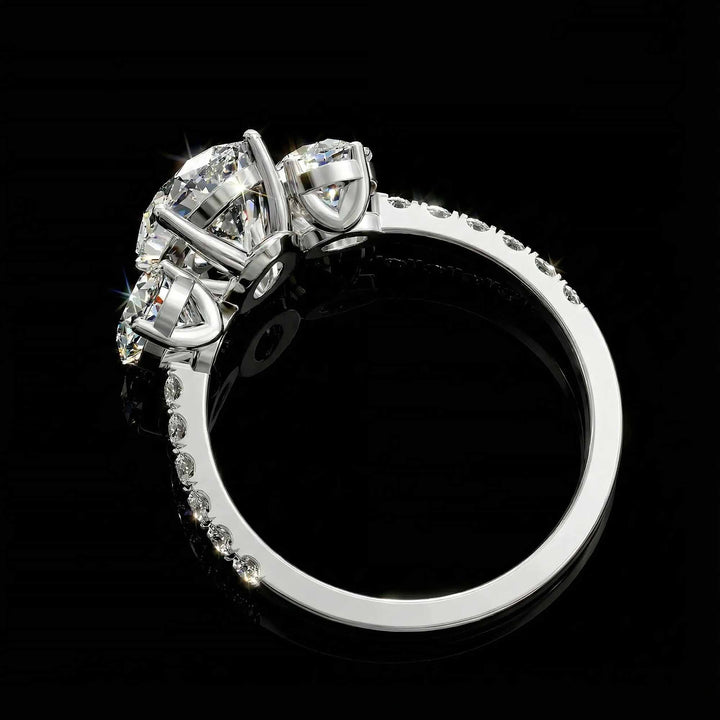 Oval diamond three stone engagement ring with round side stones and pavé band on display.