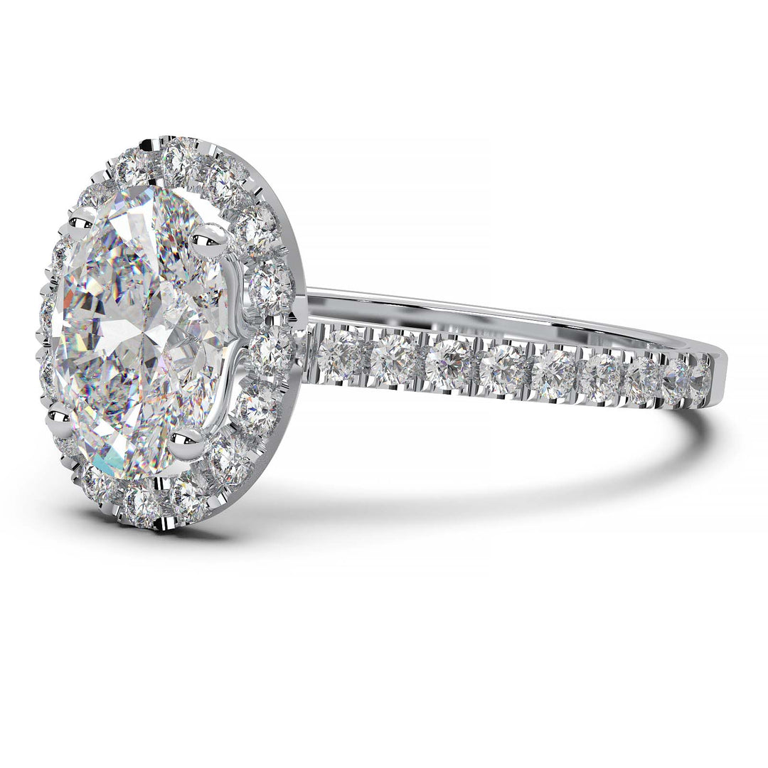 Oval lab-grown diamond halo engagement ring with pavé diamonds on the band in a cathedral setting.