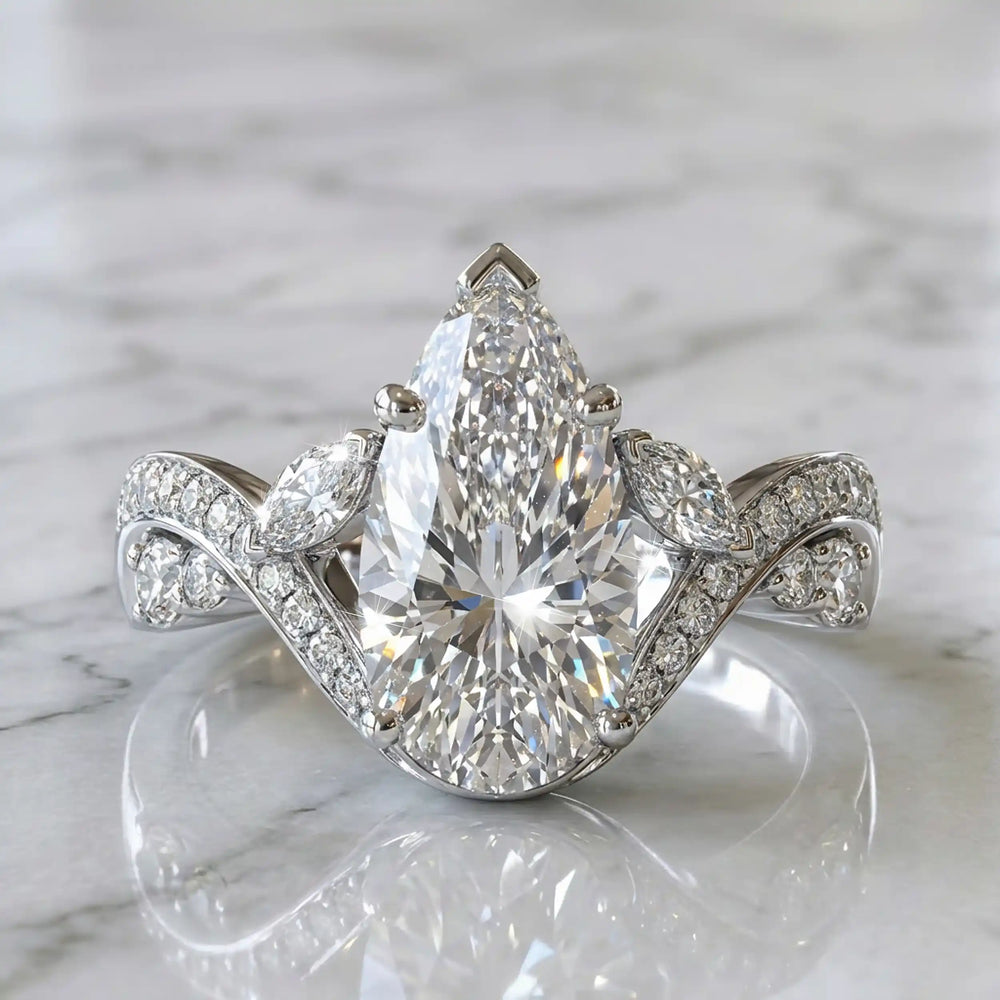 3 carat pear lab diamond twisted three-stone engagement ring displayed on marble surface.
