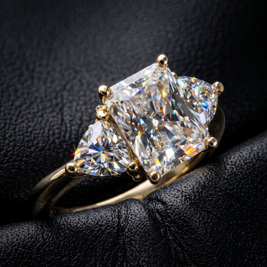 Radiant-cut moissanite ring with trillion side stones set in 14K yellow gold.