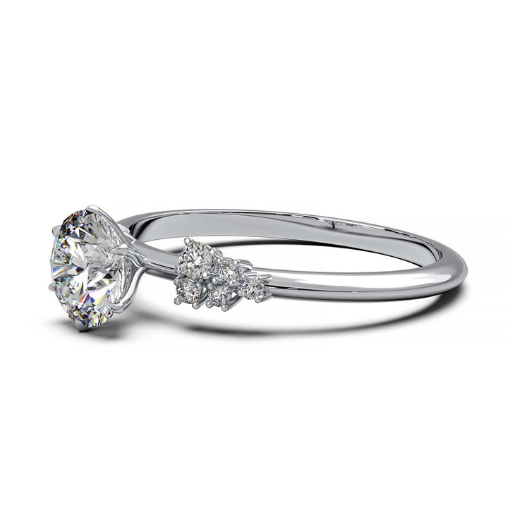 Dainty engagement ring with 0.7 carat round lab-grown diamond in a cluster setting, featuring side diamonds.