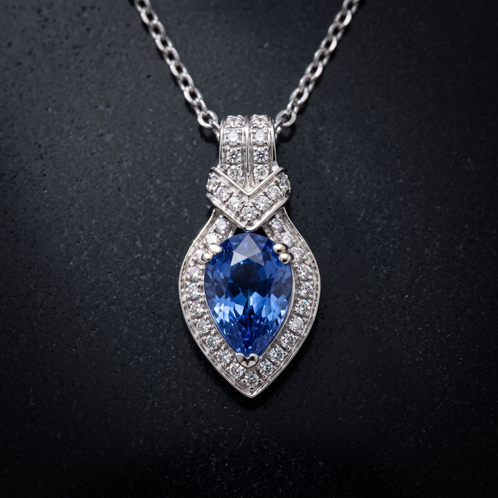 Pear-cut blue sapphire pendant with diamond halo in 14K white gold.