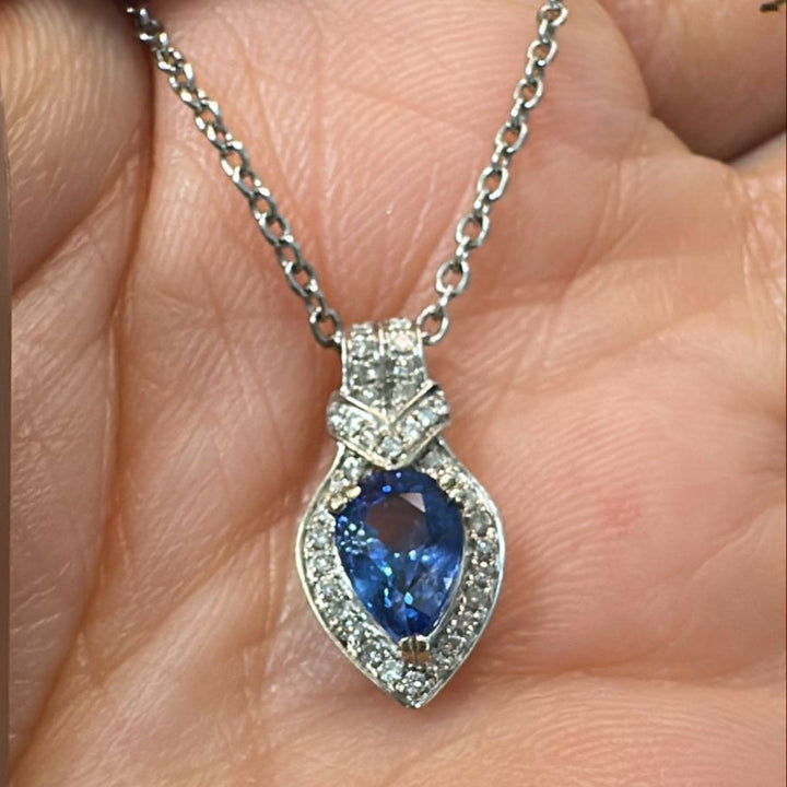 Pear-cut blue sapphire pendant with diamond halo in 14K white gold.