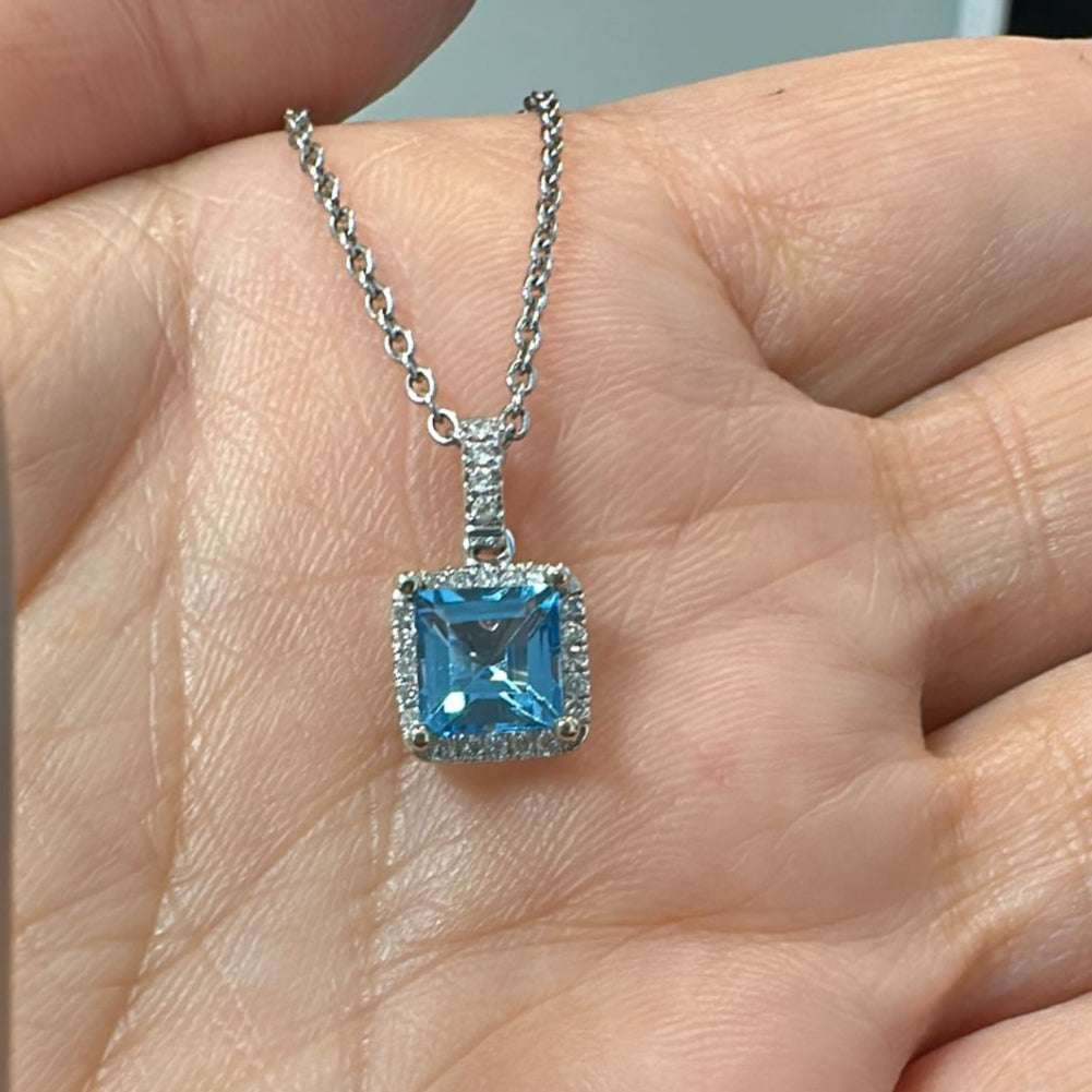 Princess-cut blue topaz pendant with diamond halo in 14K white gold.