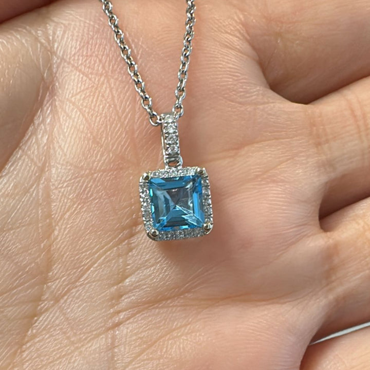 Princess-cut blue topaz pendant with diamond halo in 14K white gold.