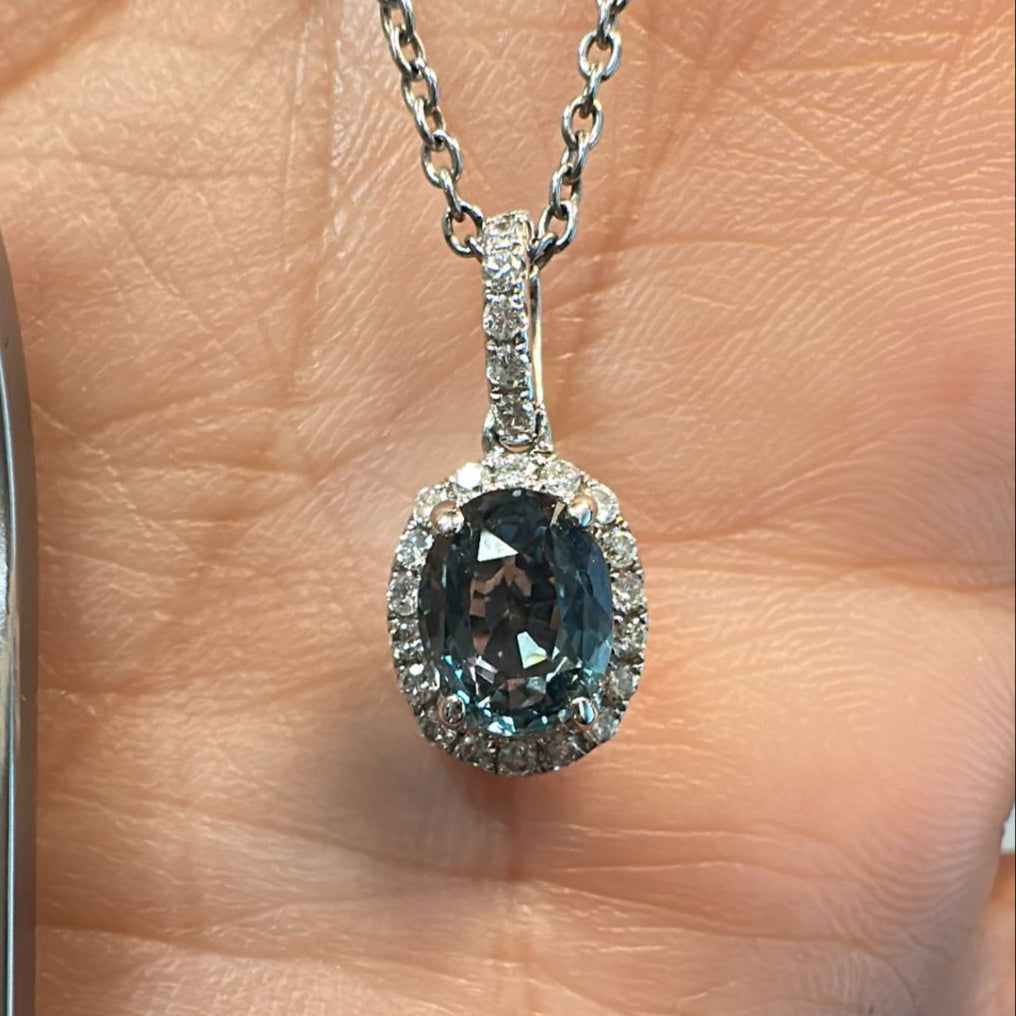 Oval-cut blue sapphire pendant with diamond halo in 14K white gold.