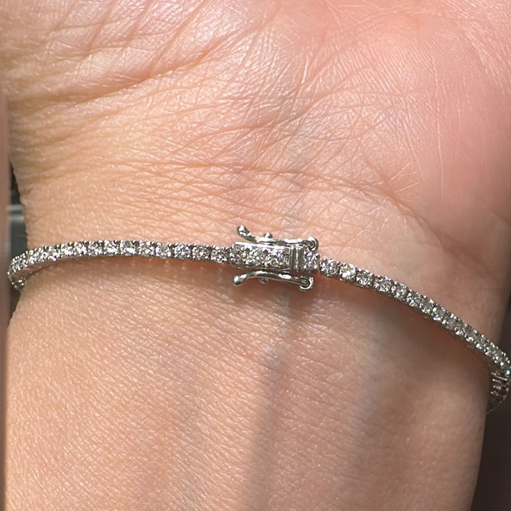 Close-up of a 14K white gold lab-grown diamond tennis bracelet with a four-prong, open-back basket-style setting, featuring 100 diamonds totaling 1.89 CT.
