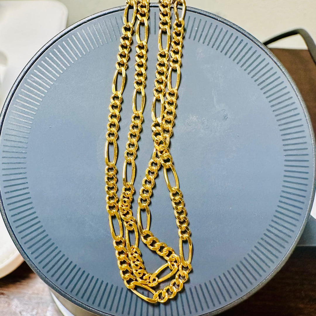 18K gold Figaro chain with alternating link design on a circular display