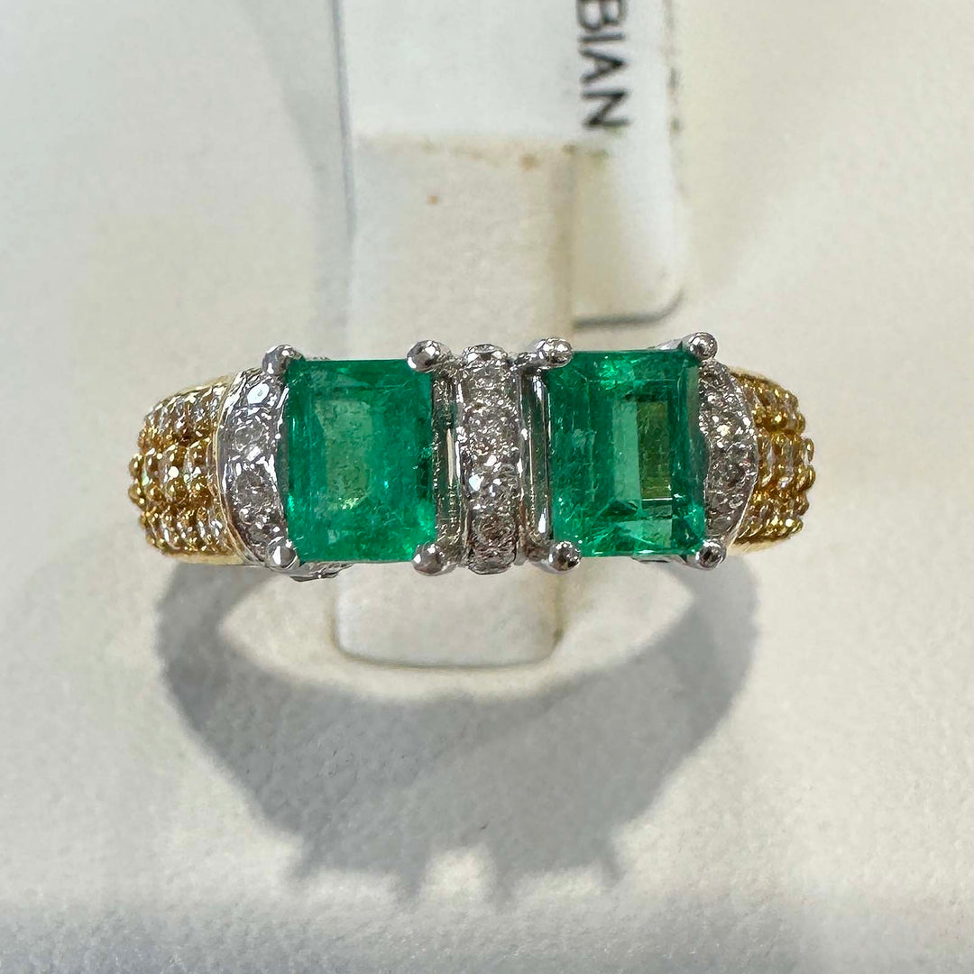 Custom double stone Colombian emerald ring in 18k yellow gold with natural diamonds.