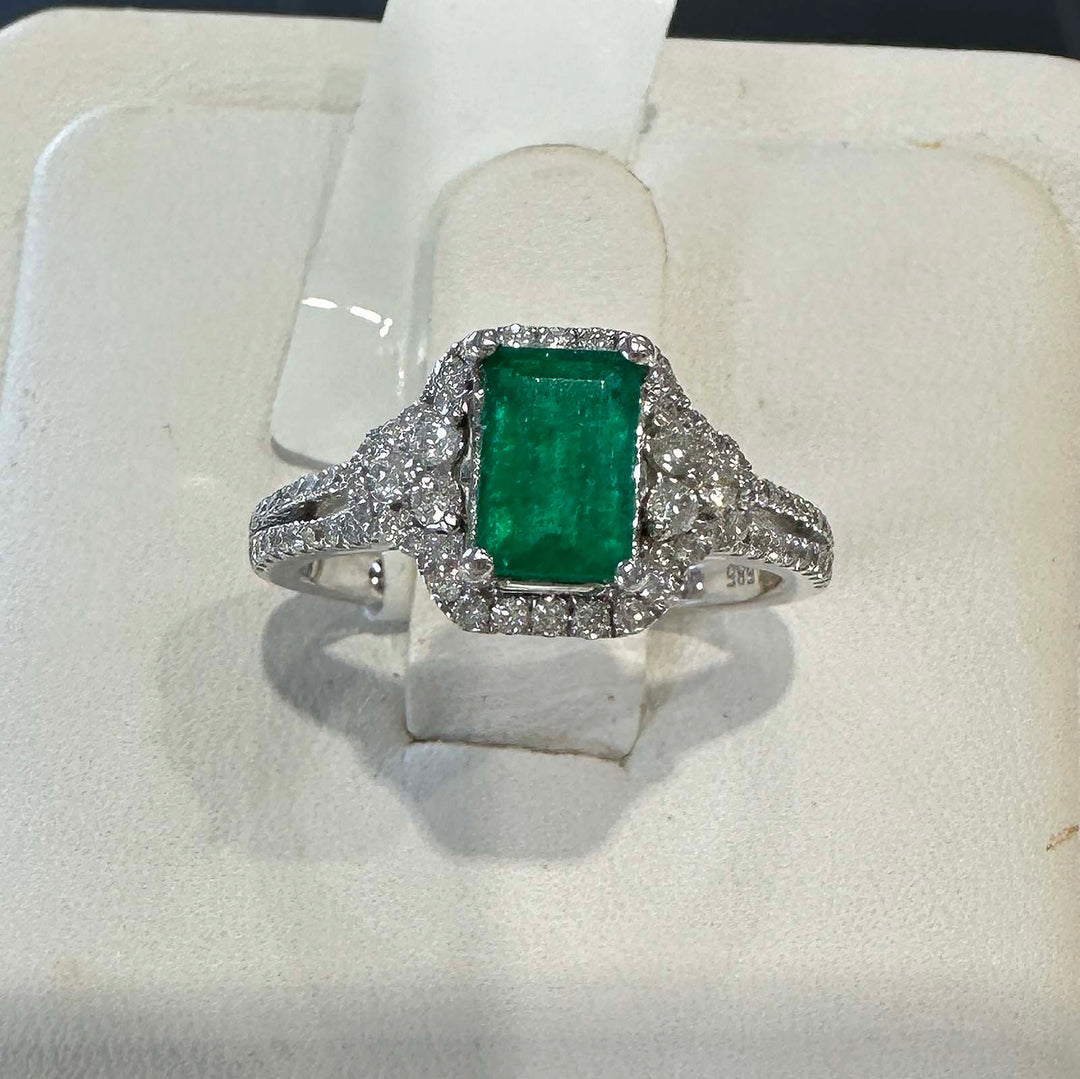 Elegant Colombian emerald ring with diamond halo in 14k white gold.