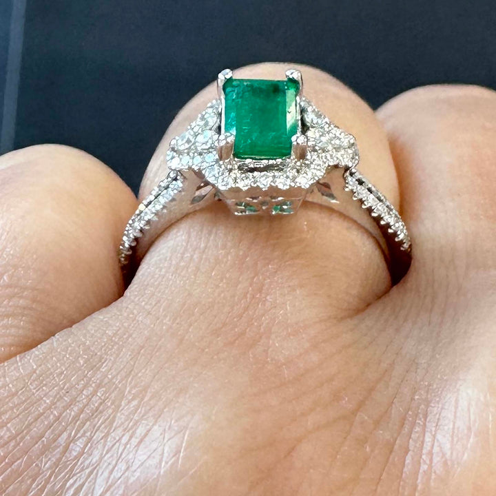 Elegant Colombian emerald ring with diamond halo in 14k white gold.