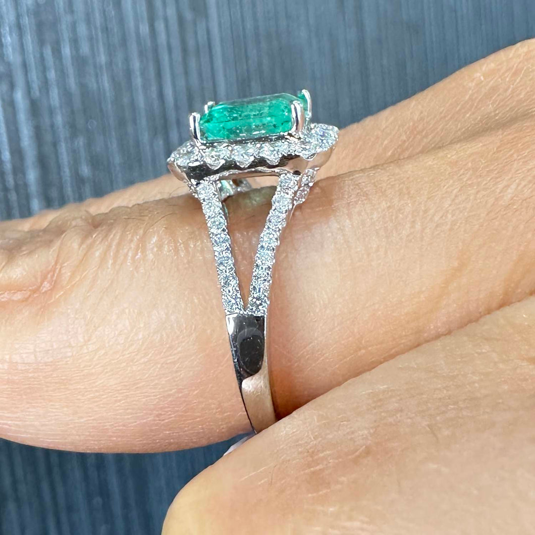 Colombian emerald ring with diamond halo and split shank in 14k white gold.