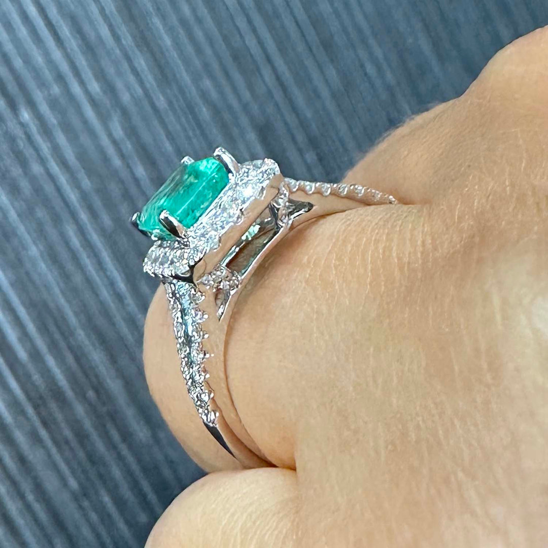 Colombian emerald ring with diamond halo and split shank in 14k white gold.