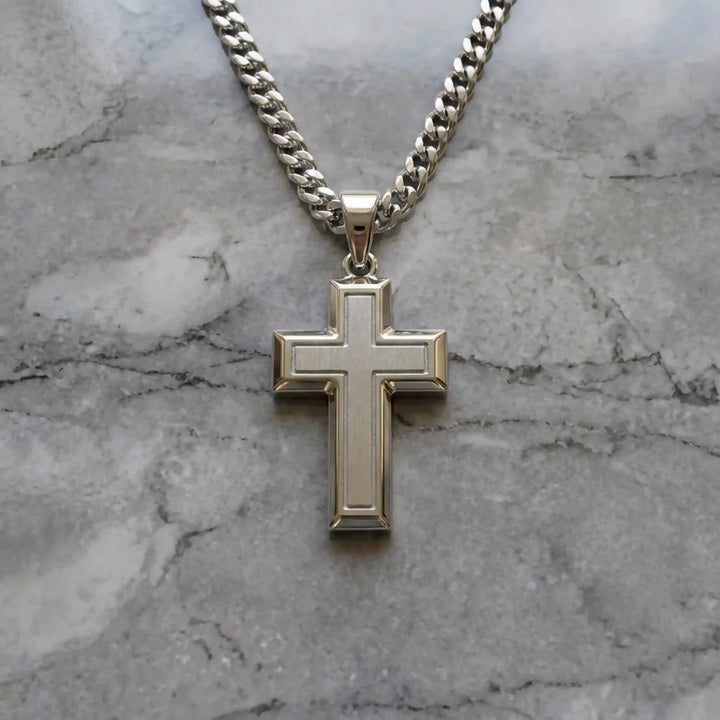 Hollow contemporary cross pendant displayed on chain over marble background.