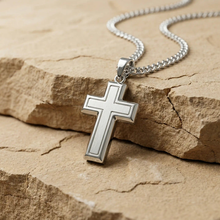 Hollow contemporary cross pendant displayed on chain overlime stone slab.