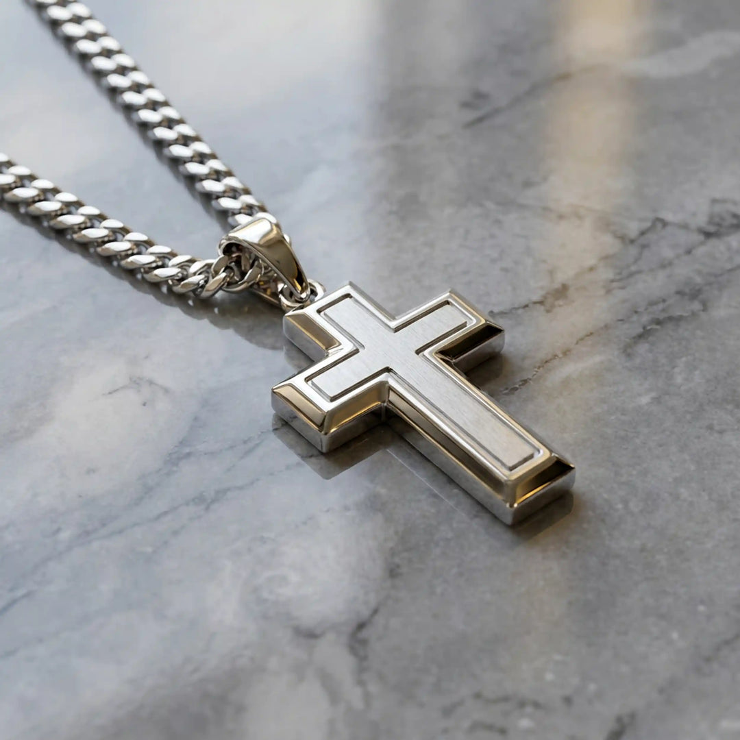 Hollow contemporary cross pendant displayed on chain over marble background.