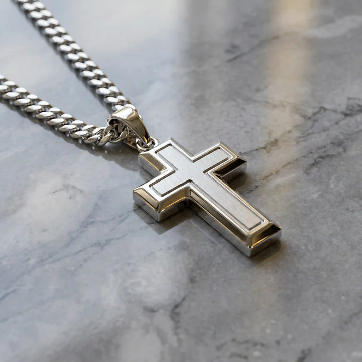 Hollow contemporary cross pendant displayed on chain over marble background.