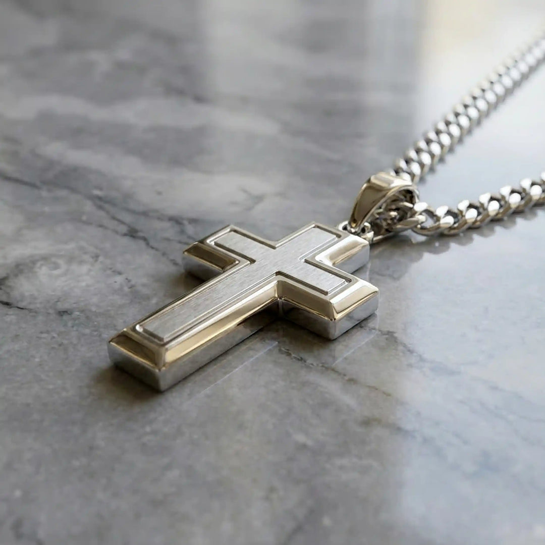 Hollow contemporary cross pendant displayed on chain over marble background.