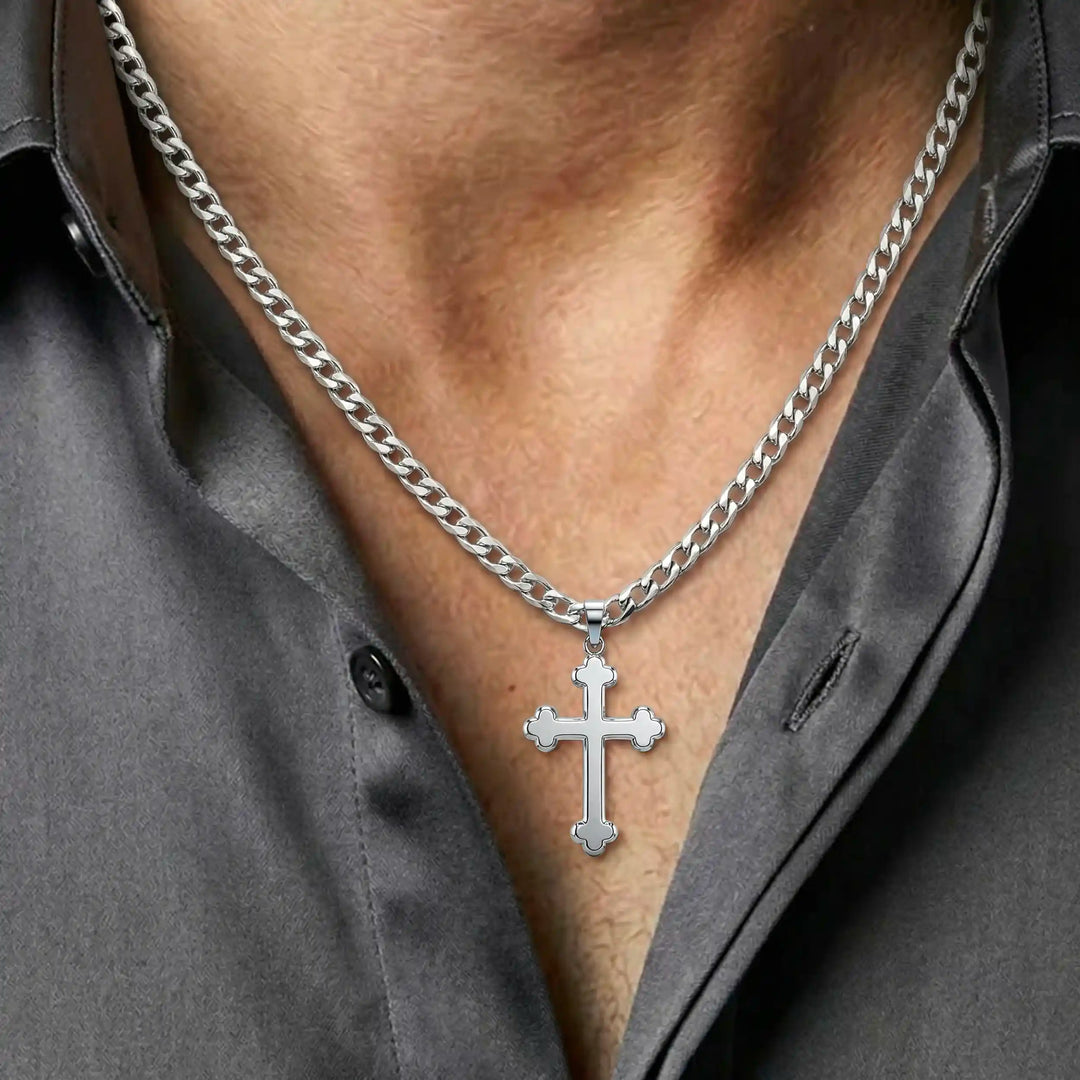 Cross fleury pendant necklace with fleur-shaped cross ends displayed on chest.