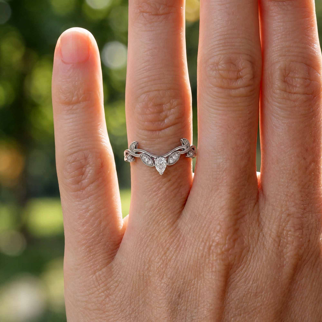 Curved wedding band with marquise and round lab-grown diamonds shown on reflective surface.