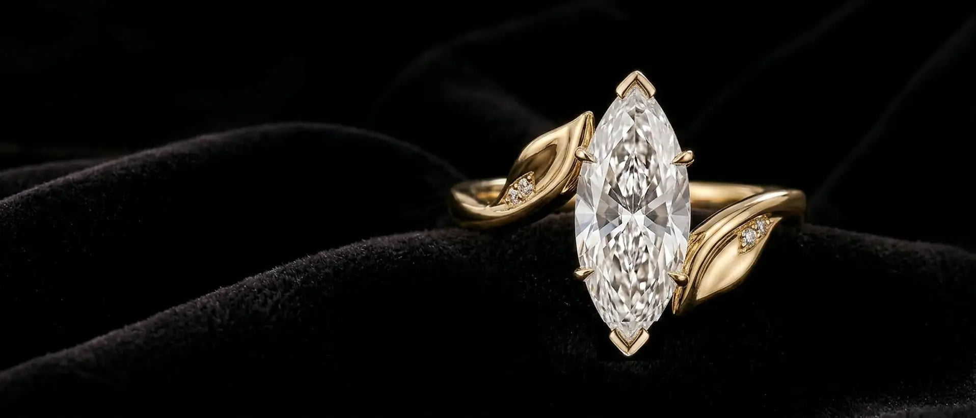 Nature-inspired yellow gold engagement ring with a marquise diamond center stone resting on black velvet