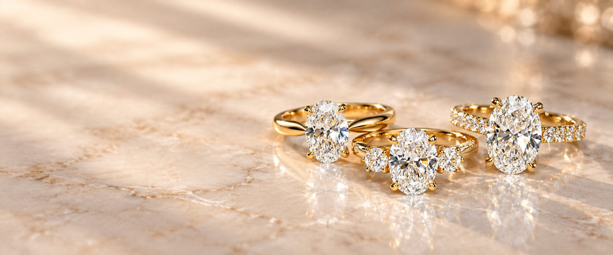 Three yellow gold oval diamond engagement rings on marble — in-store engagement rings 20% off at Rudix Jewellery Hamilton