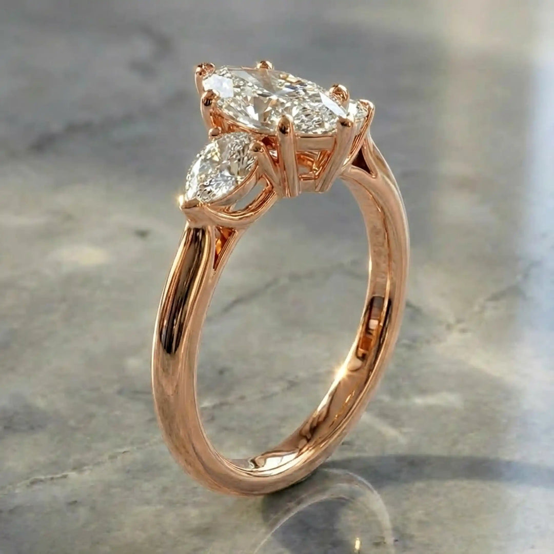 Marquise lab-grown diamond three-stone engagement ring with pear side stones on a polished surface.
