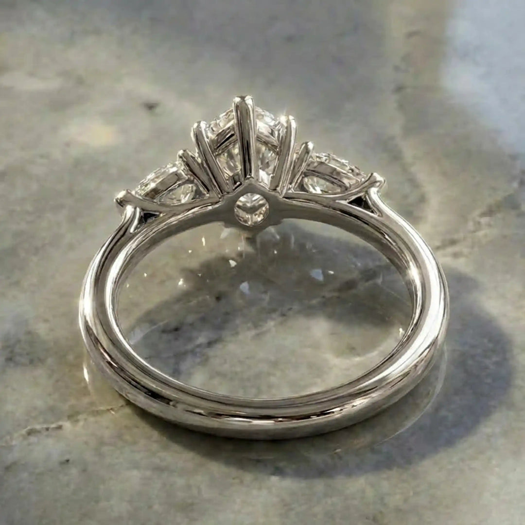 Marquise lab-grown diamond three-stone engagement ring with pear side stones on a polished surface.
